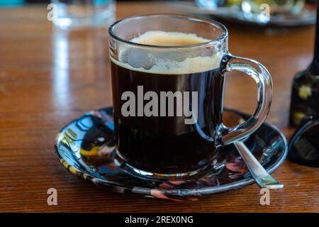 Americano without sugar Hot Beverage in a Glass Cup served with saucer and spoon Stock Photo
