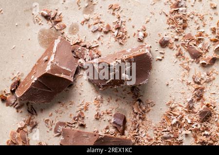 broken and crumbled natural chocolate, edible milk chocolate made from cocoa and sugar, pieces of chocolate randomly scattered on the table Stock Photo