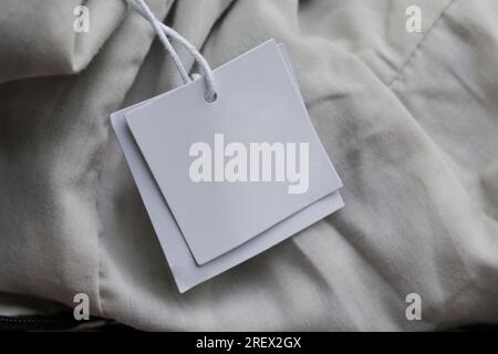 Close up of price tag of clothing item. Blank label tag mockup on clothes. Fashion industry and retail concept. Stock Photo