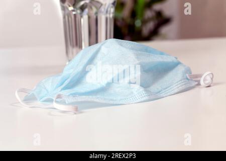 disposable medical mask on a white table, close up of medical items to protect the respiratory system from dust and viruses Stock Photo