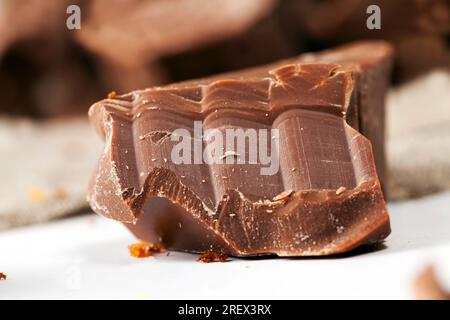 broken into several parts pieces of chocolate from cocoa, natural food from cocoa, sugar, cocoa butter, pieces of large natural real chocolate Stock Photo