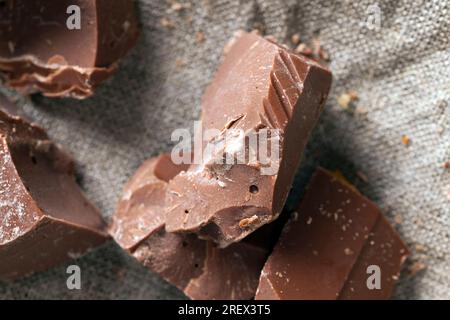 broken and crumbled natural bitter chocolate, edible bitter chocolate made from cocoa and sugar, pieces of bitter chocolate are randomly scattered on Stock Photo