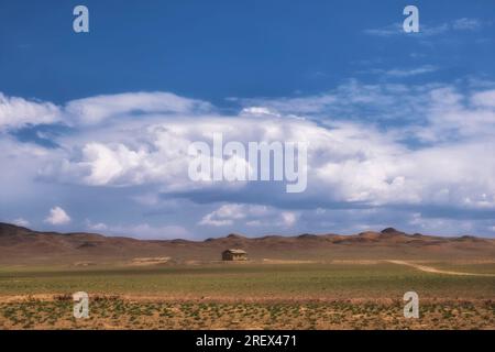 small lonely clay house in the desert under a cloudy sky Stock Photo