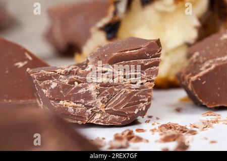 edible bitter chocolate made from cocoa and sugar, pieces of bitter chocolate are randomly scattered on the table, broken and crumbled natural bitter Stock Photo