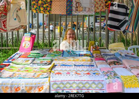 Niteroi, Brazil,  An adult Brazilian woman sells beautiful textile objects in a kiosk or market stall. The craft products have patterns and attractive Stock Photo