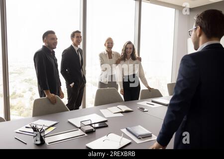 Cheerful business team and business leader standing at large table Stock Photo