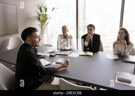 Confident male professional talking to coworkers on corporate meeting Stock Photo