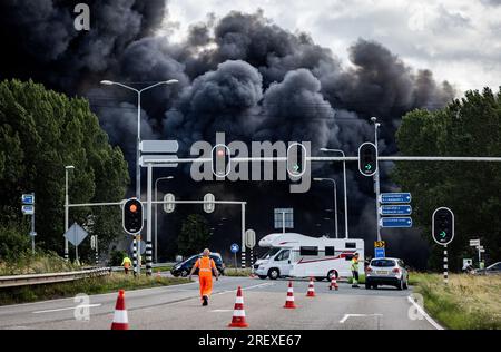 Alblasserdam, Netherlands. 30th July 2023. ALBLASSERDAM - A closed A15 near Alblasserdam due to a very large fire on the roof of a storage company in Alblasserdam causes a lot of smoke development. The fire is raging on a roof with solar panels. Photo: ANP / Hollandse hoogte / Jeffrey Groeneweg netherlands out - belgium out Credit: ANP/Alamy Live News Stock Photo