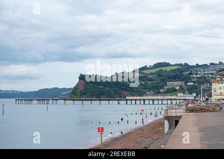 Teignmouth, England – July 21, 2023: Landscape view of the Devon resort town’s promenade, beach and Victorian pier facing the English Channel Stock Photo