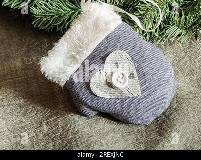 One New Year's toy. Christmas toy in the form of decorative fabric soft mitt of gray color. Decor for Christmas tree. Beautiful Christmas background. Stock Photo