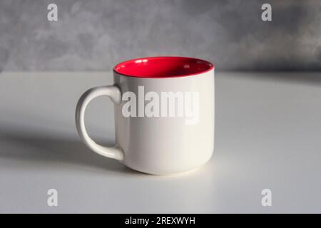 White ceramic tea cup red inside on the kitchen table Stock Photo
