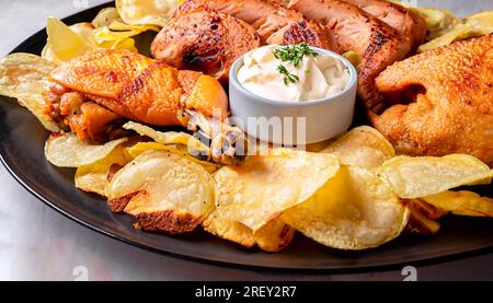 A closeup shot of a Spanish dish consisting of potato chips and roasted chicken with aioli Stock Photo