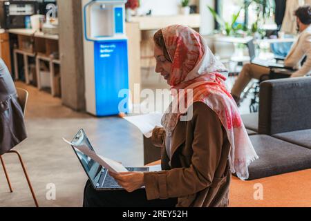 Muslim female company operator working on lap top computer analyzing growth, charts, statistics and data. Back view photo Stock Photo