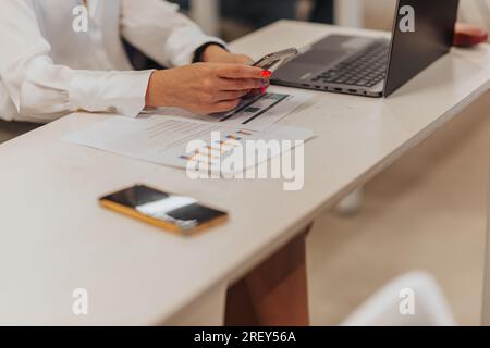 Close up shot of woman checking phone while sitting on working desk Stock Photo