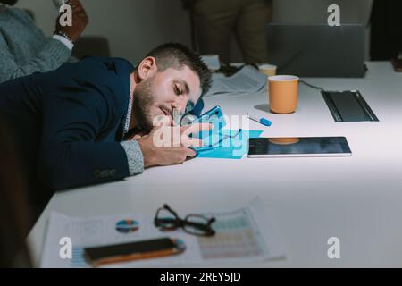 Close up of tired business man looking at the phone  while laying on the business table at the cop working place Stock Photo