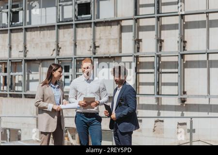 Young architecture team working together, discussing in a construction area Stock Photo