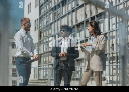 Three young architectures working in the city, planning, discussing work. Architectures having meeting outdoors, discussing new project Stock Photo