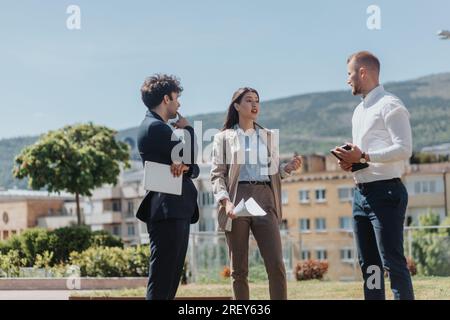 Young, stylish business partners discussing work out in the city. Businesswoman explaining project to her male coworkers Stock Photo