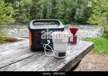 Electric Coffee Pot and Portable Power Station on campground picnic table Stock Photo