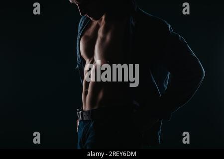 Muscular and good-looking man standing in a dark room and posing Stock Photo