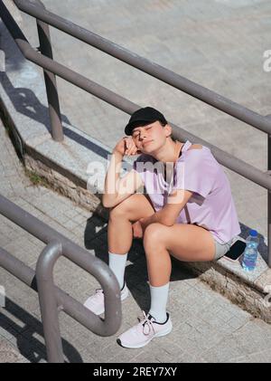 Sportsgirl faced to the sun with closed eyes. She is taking a break from training Stock Photo