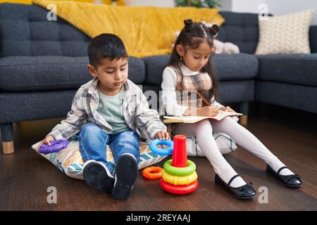 Adorable boy and girl playing with hoops game sitting on sofa at home ...