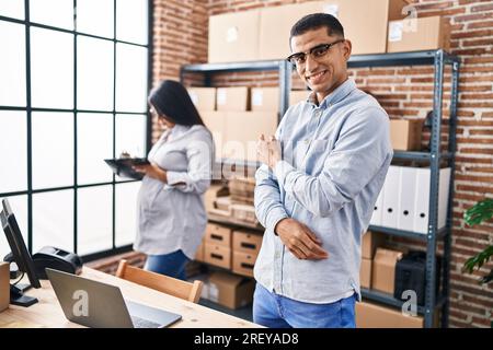 Young hispanic couple expecting a baby working at small business ecommerce smiling happy pointing with hand and finger Stock Photo