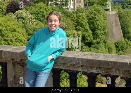 The sun is too bright for the photo. The girl squints in the bright sun on a walk in the city Stock Photo
