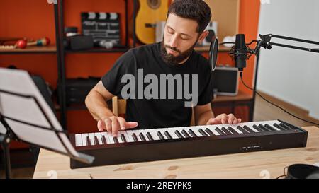 Young hispanic man musician playing piano at music studio Stock Photo