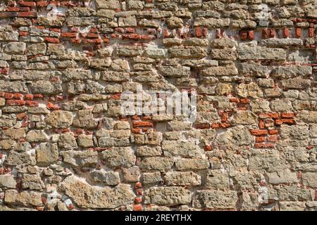 Old red brick wall background. Texture of an old ancient stone wall. Stonewall background. Stock Photo