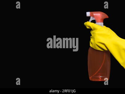 Hand in yellow rubber gloves with a container of detergent.  close up. On black background. copy space. banner Stock Photo