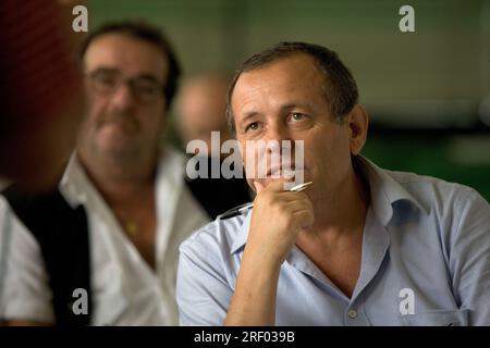 Two men attentively listening during a discussion, one holding a pen, the other in the background slightly blurred. Stock Photo