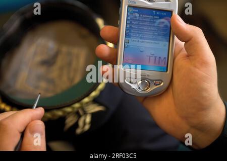 A person using a stylus on a Qtek Pocket PC displaying the date September 12, 2005. Stock Photo