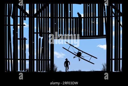 A barnstorming bi-plane flies low and is seen through the doorway of an old farm barn in an illustration about the 1920s aerial shows. Stock Photo