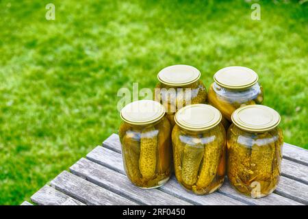 Canned pickled cucumbers in jars covered with lids. Homemade food. Stock Photo