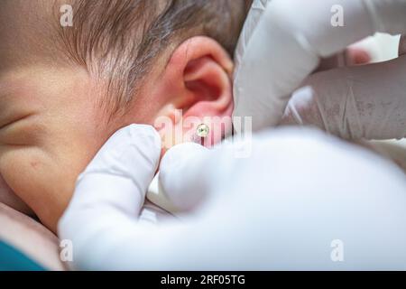 Piercing a newborn's ear to put an earring Stock Photo