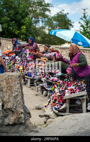 Cappadocia, Turkey - September 13, 2021: Several women selling dolls and souvenir right outside the Derinkuyu underground city of caves in Cappadocia, Stock Photo