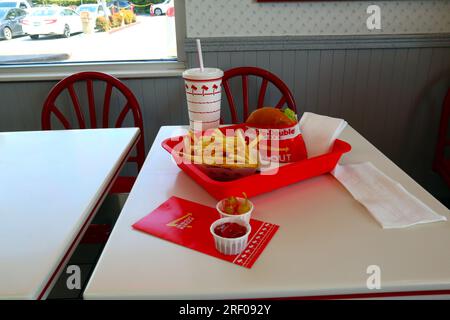 IN-N-OUT Burger - Hamburger and french fries after finished eating in a tray on the table inside the fast-food restaurant Stock Photo