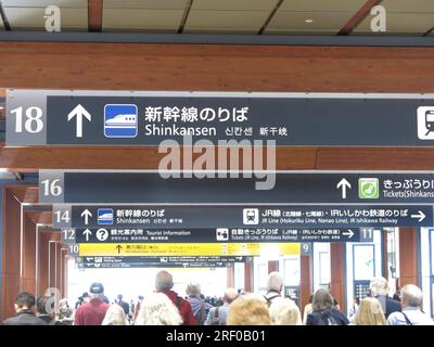 Passengers follow the overhead signs to the Shinkansen or Bullet Train at Kanazawa Station for their train to Tokyo, Japan. Stock Photo