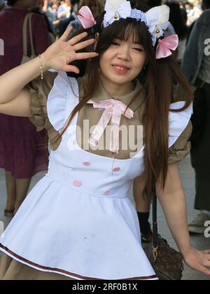 A Japanese young woman in 'cute style' pinafore dress poses to take selfies whilst visiting Senso-ji Temple, a key tourist landmark in Tokyo. Stock Photo