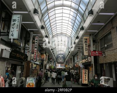 The covered arcade of Shin Nakamise shopping street in the busy tourist area of Asakusa is filled with shops & restaurants. Stock Photo