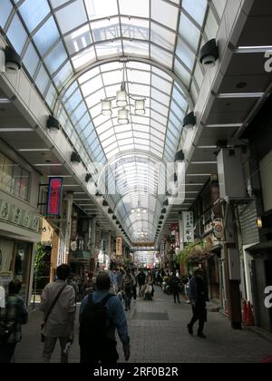 The covered arcade of Shin Nakamise shopping street in the busy tourist area of Asakusa is filled with shops & restaurants. Stock Photo