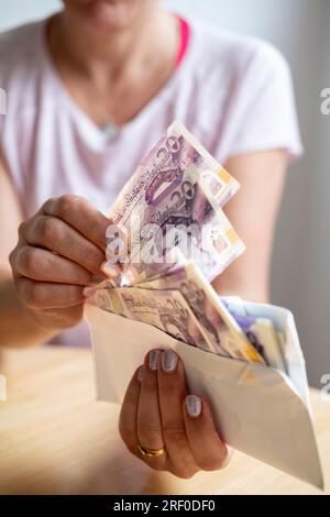 Woman taking out money from her savings, cost of living Stock Photo