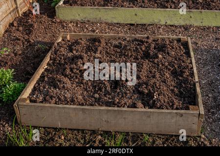 Soil filled wooden raised flower beds. The beds are empty ready for planting. Stock Photo