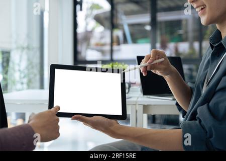 Mockup image of two student holding black tablet with blank desktop white screen while study at table in livingroom Stock Photo