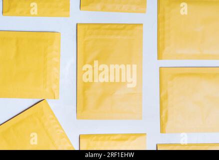 A top-down view of a set of yellow soft envelopes with padding placed neatly side by side on a concrete table. Stock Photo