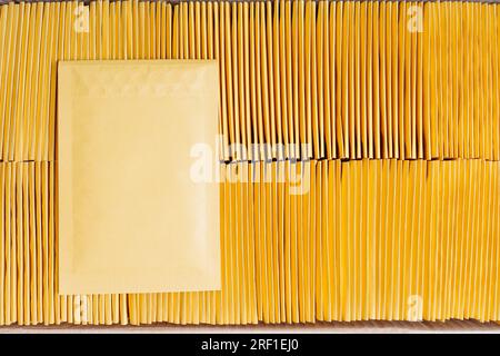 Close-up of a shipping cardboard box filled with padded envelopes and one yellow mailer placed on top. Stock Photo
