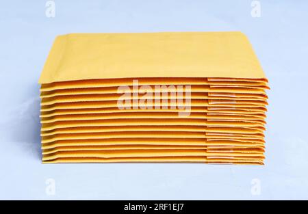 Close-up of yellow padded envelopes stacked on a grey concrete background. Stock Photo