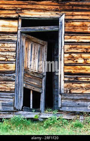 Abandoned old log house with a broken door Stock Photo