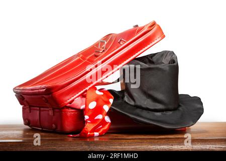 A red suitcase with a magician's hat and a red cloth on a white background. Background for magician and practical joke. Stock Photo